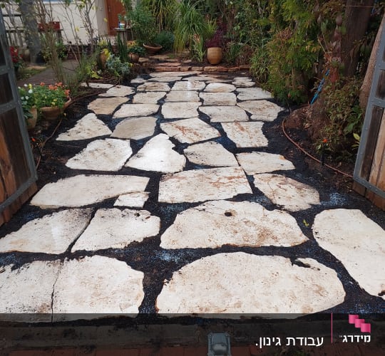 אבנים גדולות מונחות בשביל בגינה עם צמחים מסביב